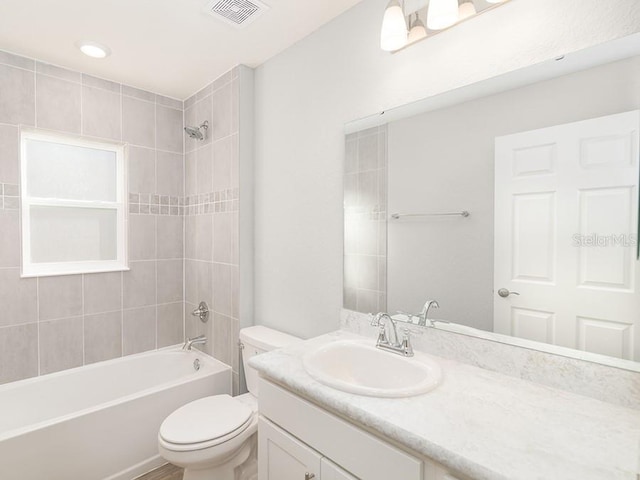 full bathroom with tiled shower / bath combo, vanity, and toilet