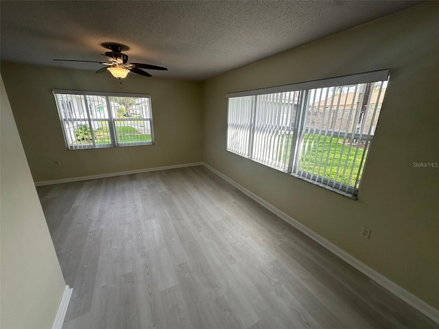 empty room featuring ceiling fan, light hardwood / wood-style floors, and a textured ceiling