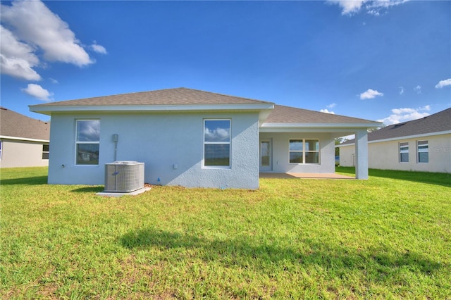 back of property with a lawn, cooling unit, and a patio area