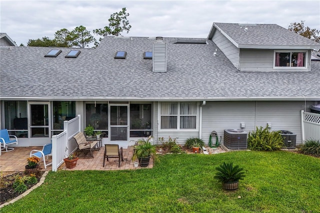 rear view of house featuring a sunroom, central AC unit, a patio area, and a lawn