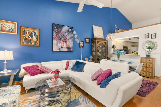 living room with hardwood / wood-style flooring, ceiling fan, and high vaulted ceiling