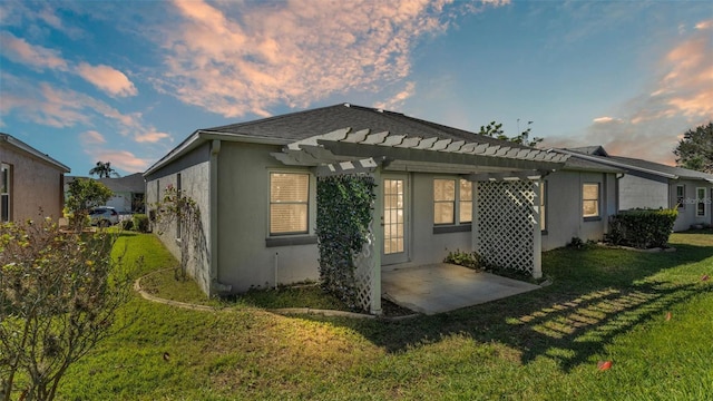 property exterior at dusk with a lawn, a patio area, and a pergola