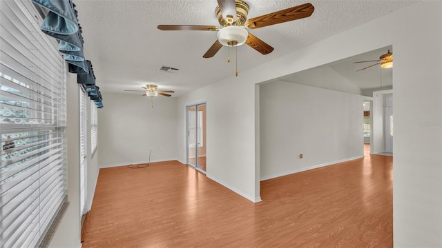 spare room with a textured ceiling, light hardwood / wood-style flooring, plenty of natural light, and vaulted ceiling