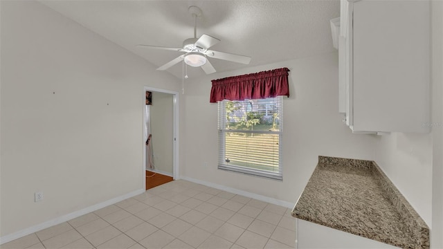 unfurnished room with a textured ceiling, ceiling fan, light tile patterned flooring, and lofted ceiling