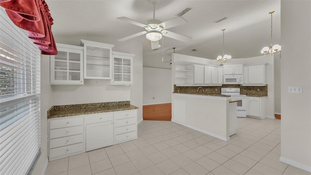 kitchen with lofted ceiling, white appliances, ceiling fan with notable chandelier, dark stone countertops, and white cabinetry