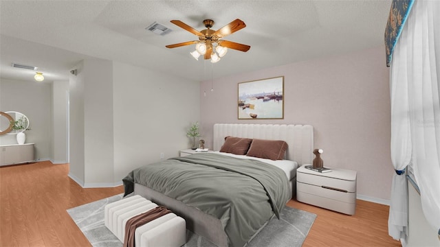 bedroom with ceiling fan, light hardwood / wood-style flooring, and a textured ceiling