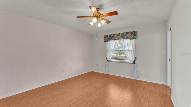 spare room with vaulted ceiling, ceiling fan, wood-type flooring, and a textured ceiling