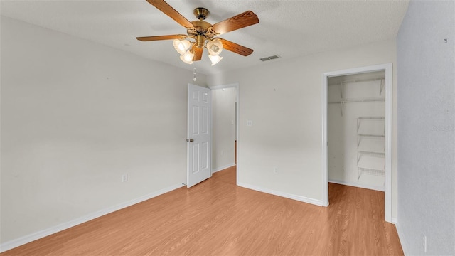 unfurnished bedroom featuring ceiling fan, a closet, a textured ceiling, and light wood-type flooring