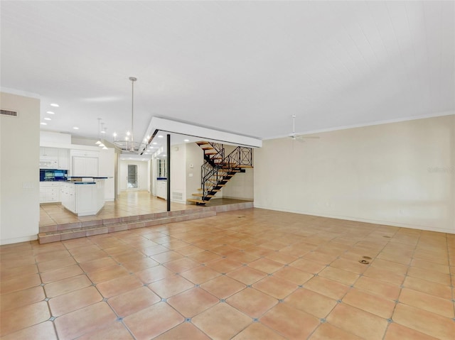 empty room with ceiling fan with notable chandelier, light tile patterned floors, and ornamental molding