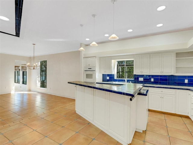 kitchen with white cabinets, light tile patterned floors, hanging light fixtures, and tasteful backsplash