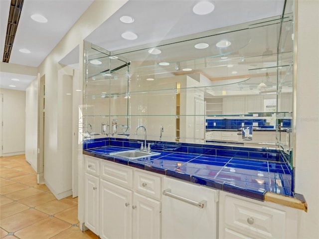 bar featuring tile countertops, white cabinetry, sink, and tasteful backsplash