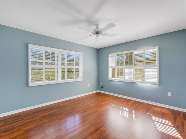 empty room with ceiling fan, a healthy amount of sunlight, and dark hardwood / wood-style flooring