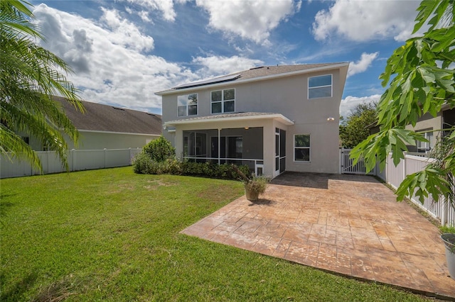 rear view of property featuring a patio area, a sunroom, and a yard