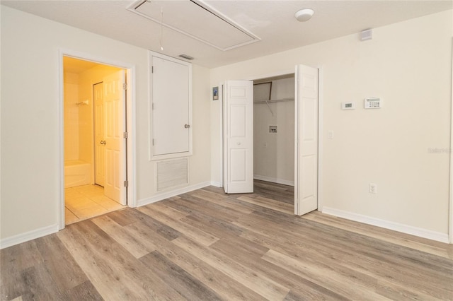 unfurnished bedroom with connected bathroom, a closet, and light hardwood / wood-style floors