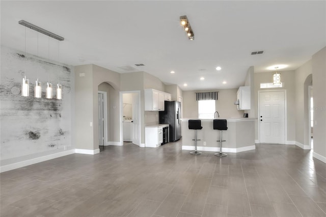 kitchen featuring stainless steel refrigerator with ice dispenser, pendant lighting, white cabinetry, and a kitchen breakfast bar