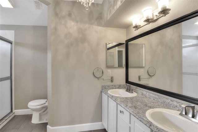 bathroom featuring a textured ceiling, vanity, toilet, and a shower with door