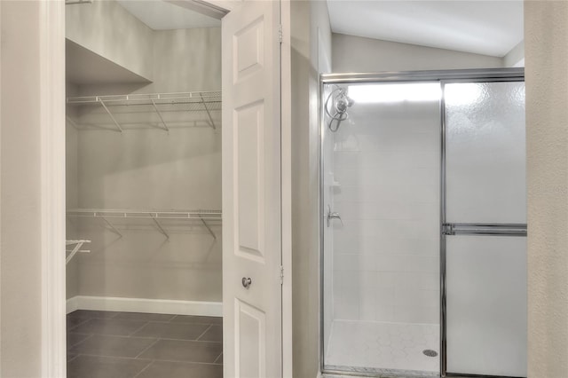 bathroom featuring tile patterned flooring, vaulted ceiling, and a shower with shower door