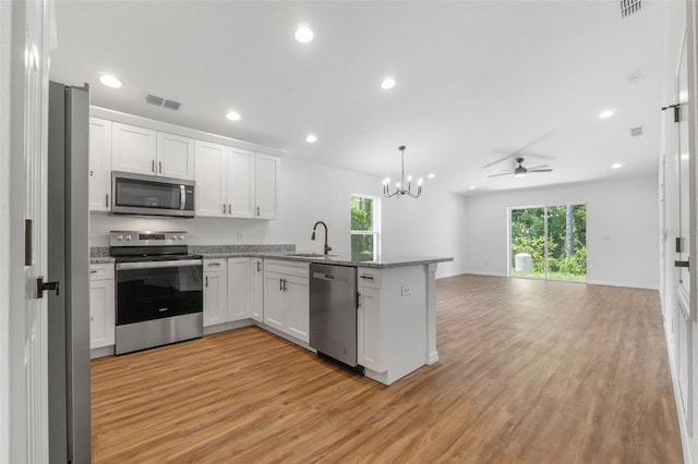 kitchen with white cabinets, ceiling fan with notable chandelier, a wealth of natural light, and appliances with stainless steel finishes