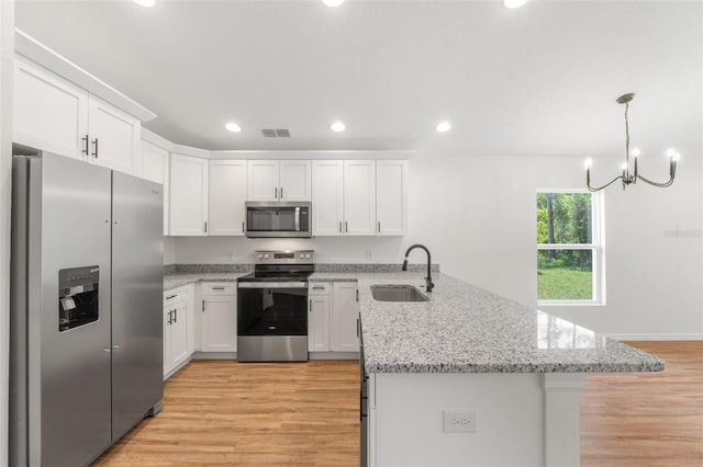 kitchen featuring white cabinetry, sink, hanging light fixtures, appliances with stainless steel finishes, and light wood-type flooring