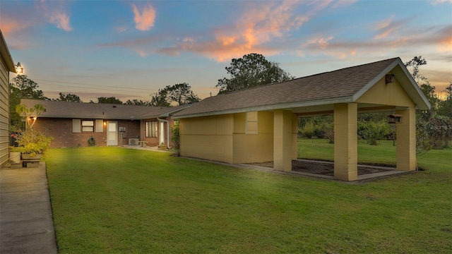 back house at dusk featuring a yard