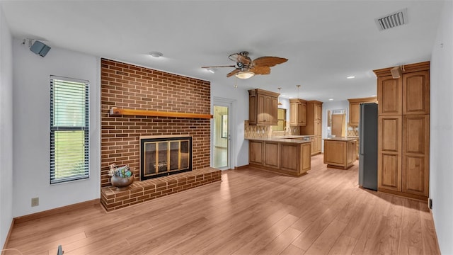 unfurnished living room with ceiling fan, a fireplace, and light hardwood / wood-style floors