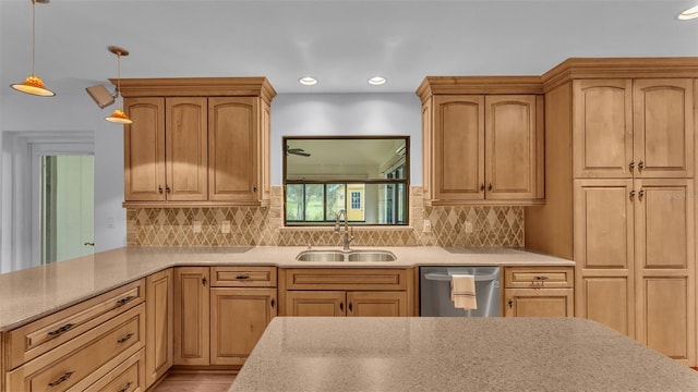 kitchen with pendant lighting, stainless steel dishwasher, light brown cabinetry, and sink