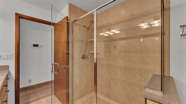 bathroom with hardwood / wood-style floors, vanity, and a shower with shower door