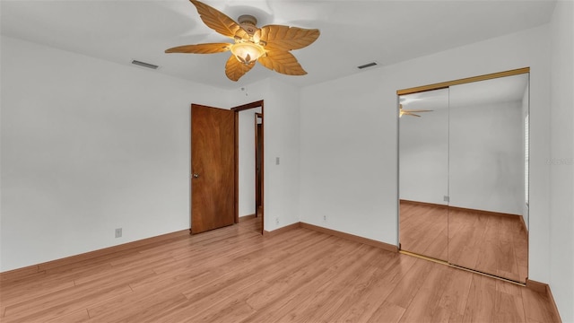 unfurnished bedroom with ceiling fan, light wood-type flooring, and a closet