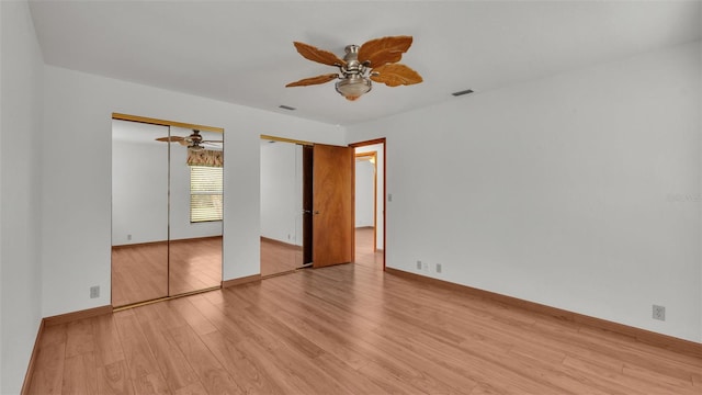 unfurnished bedroom with ceiling fan, two closets, and light hardwood / wood-style flooring