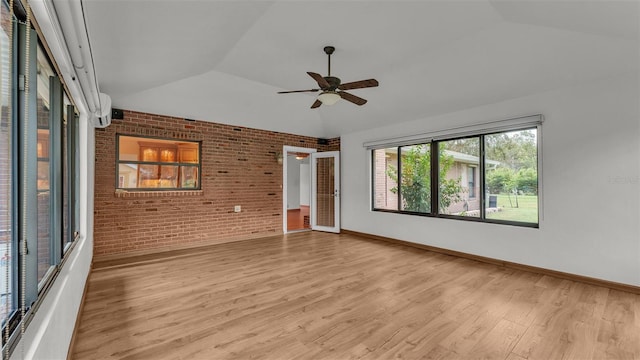 unfurnished room featuring ceiling fan, light hardwood / wood-style floors, brick wall, and vaulted ceiling