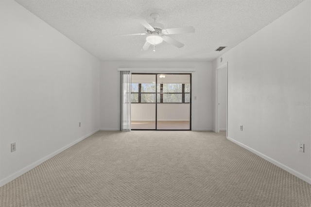 spare room with a textured ceiling, light colored carpet, and ceiling fan