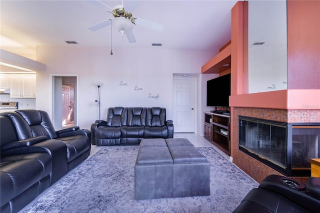 living room with a fireplace, light tile patterned floors, and ceiling fan