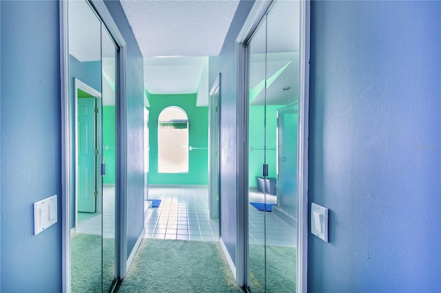 corridor featuring light colored carpet and a textured ceiling