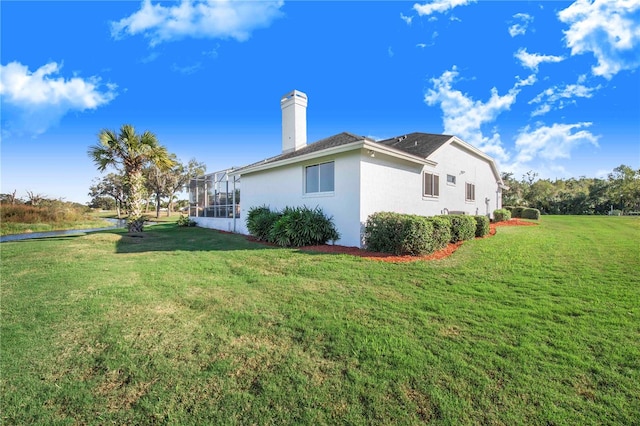 view of side of property featuring a lanai and a yard