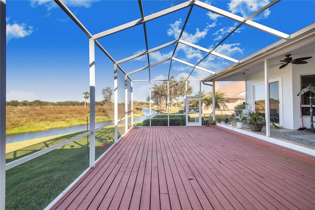 wooden deck with a yard, a water view, glass enclosure, and ceiling fan