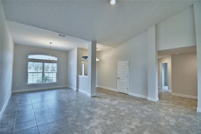 tiled empty room featuring a towering ceiling and a notable chandelier