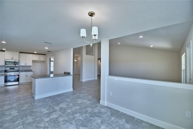 kitchen featuring appliances with stainless steel finishes, white cabinetry, a notable chandelier, decorative light fixtures, and vaulted ceiling