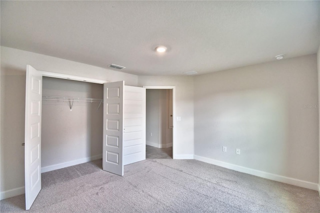 unfurnished bedroom featuring light colored carpet and a closet