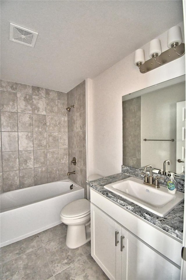 full bathroom with vanity, tiled shower / bath combo, and toilet