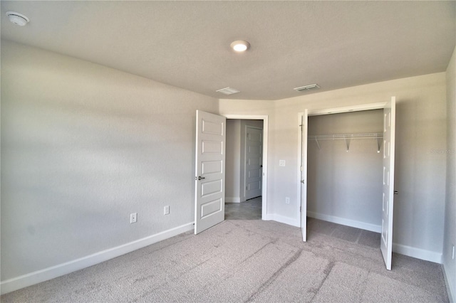 unfurnished bedroom with light carpet and a closet