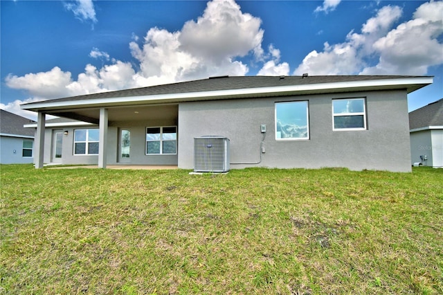 rear view of property with central AC and a lawn