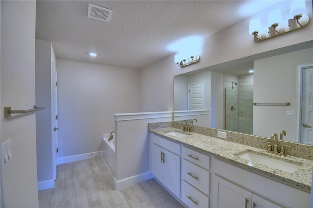 bathroom featuring a stall shower, visible vents, a sink, and a textured ceiling