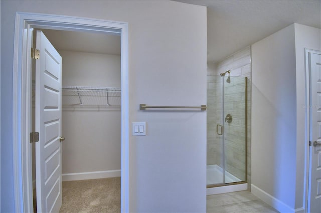 full bathroom featuring a stall shower, baseboards, and a spacious closet