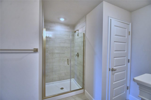 full bath featuring a shower stall and baseboards