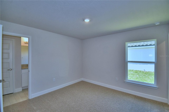unfurnished room with light colored carpet and baseboards