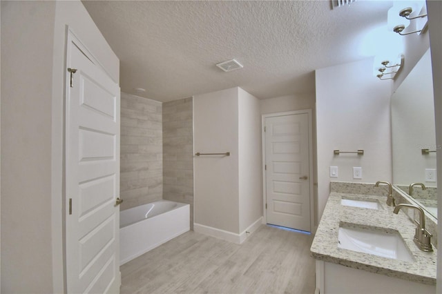 full bath featuring visible vents, a textured ceiling, a sink, and wood finished floors