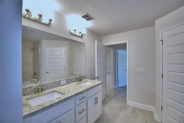 full bath featuring visible vents, wood finished floors, a sink, and a textured ceiling