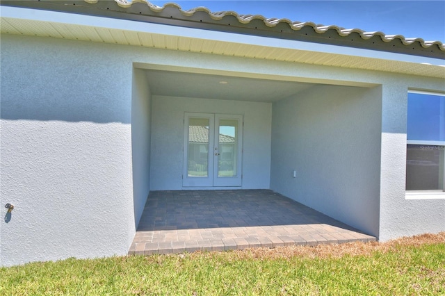 property entrance featuring stucco siding and french doors