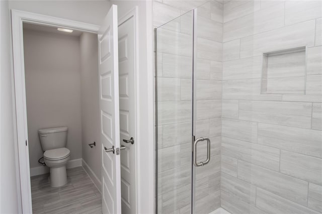 bathroom with toilet and an enclosed shower