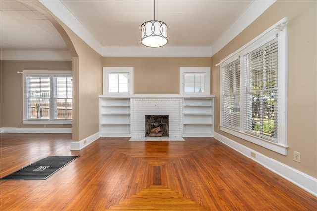 unfurnished living room featuring plenty of natural light, ornamental molding, a fireplace, and parquet floors